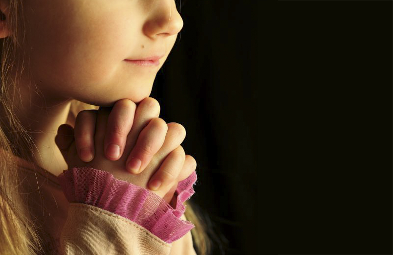 Little girl praying, eyes closed