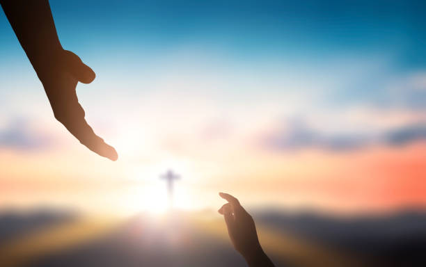 Help hand of God reaching over blurred cross on sunrise background