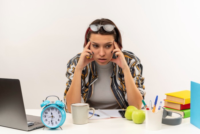thoughtful-young-student-girl-wearing-glasses-head-sitting-desk